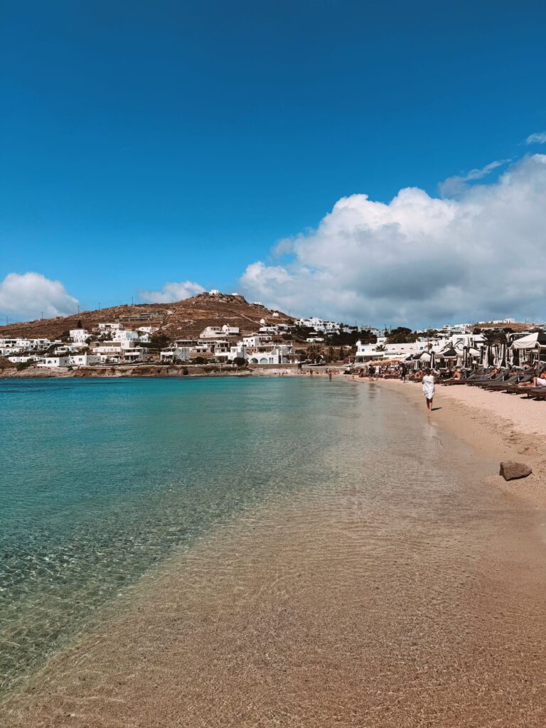 Sandy Mykonos beach with turquoise water and whitewashed houses